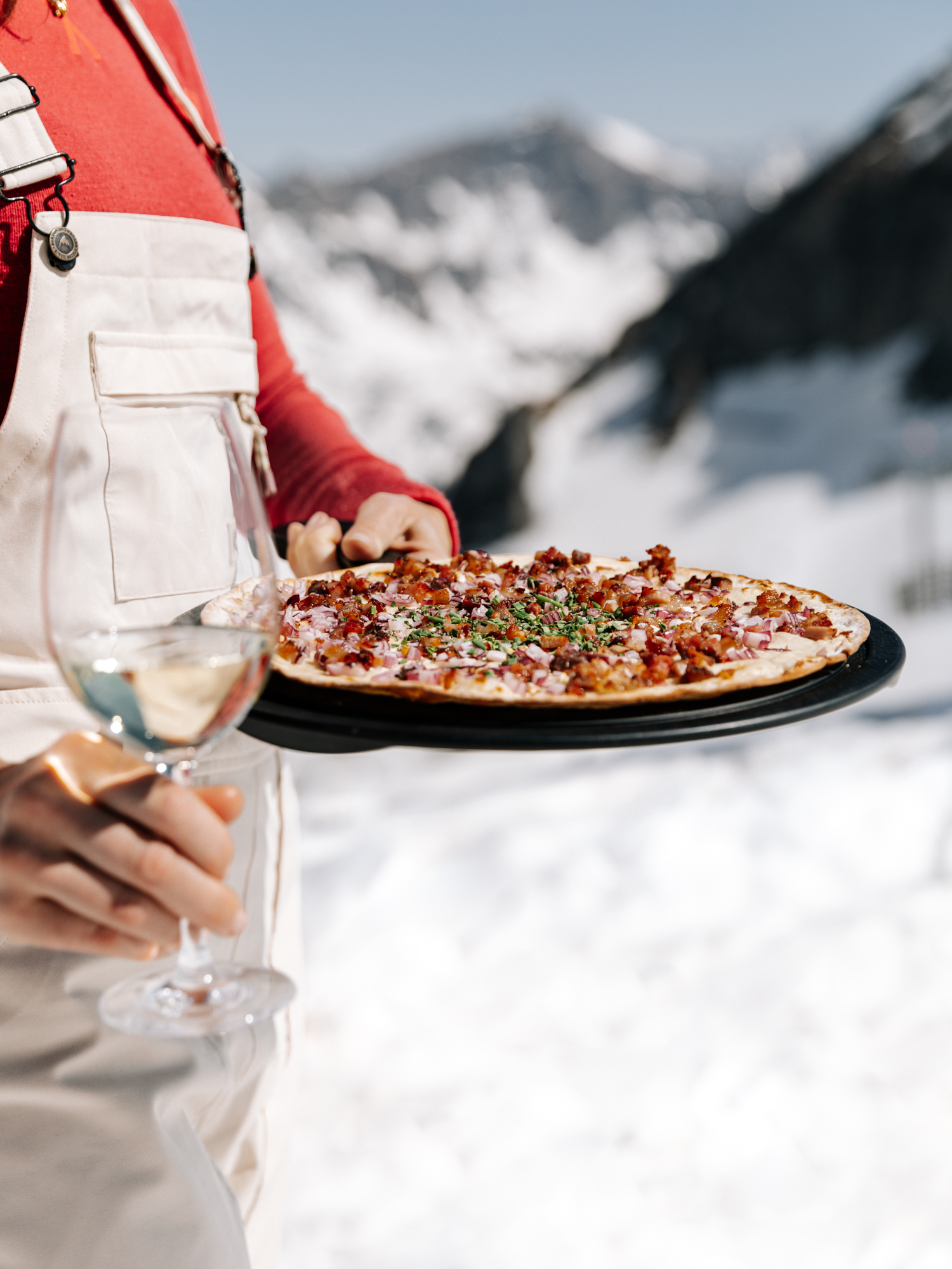 Flammkuchen mit Speck und einem Glas Weißwein in den Bergen von Obertauern