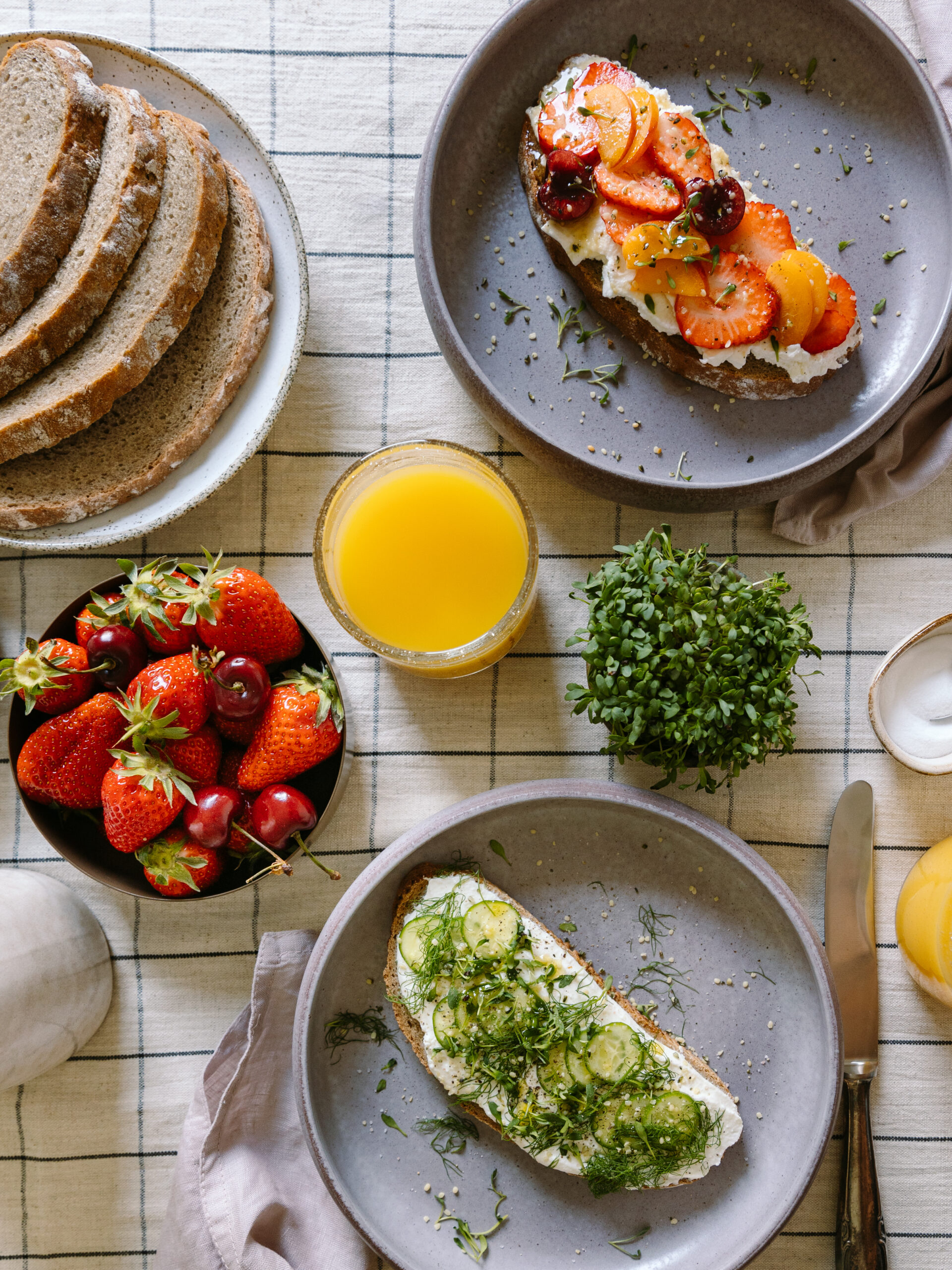 gedeckter Frühstückstisch, karierte Tischdecke, Erdbeeren, Kresse, Orangensaft im Glas